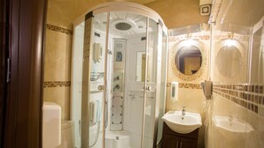 A modern bathroom with a glass-enclosed shower, a toilet, a sink, and a mirror with a decorative frame. - Junior Suite - One space Apartment (Kryonérion, limni plastira, karditsa)