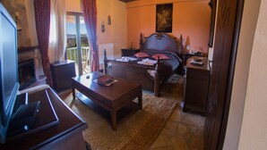 A bedroom with a bed, a desk, a chair, a TV, and a window with curtains. - Junior Suite - One space Apartment (Kryonérion, limni plastira, karditsa)