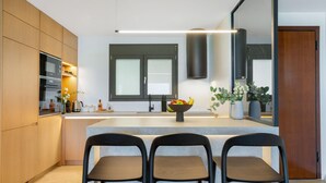 Eine moderne Küche mit Holzausstattung, einer zentralen Kochinsel, Barhocker und einem großen Fenster.