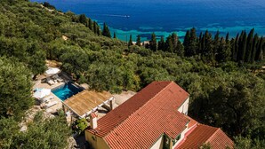 Une propriété située sur la côte, dotée d’une piscine, d’un bâtiment au toit rouge et offrant une vue sur la mer.