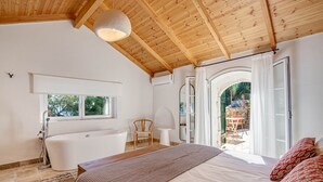 Une chambre avec un grand lit, une baignoire et un plafond en bois.