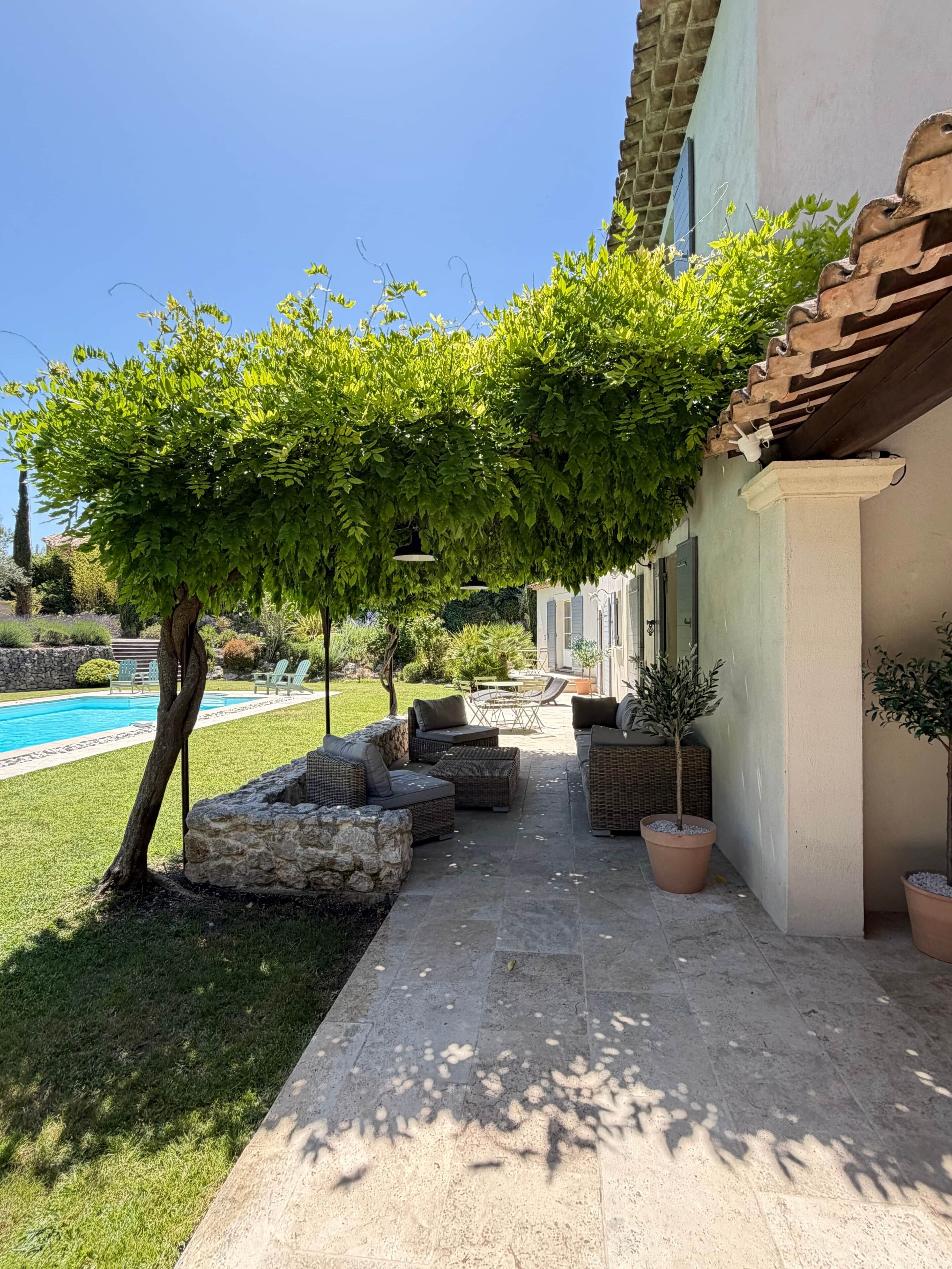 A patio area with outdoor furniture, a swimming pool, and a tree.