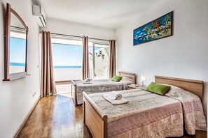 A hotel room with two beds, a large window with curtains, a painting on the wall, and an air conditioning unit. - Atlantic Sul in Albufeira (Albufeira)