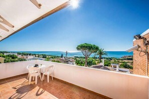 A balcony with a view of the sea, a table with chairs, and a brick wall. - Atlantic Sul in Albufeira (Albufeira)