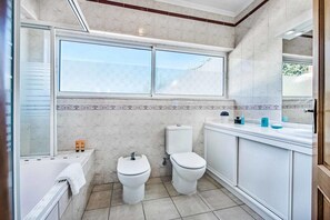 A bathroom with a bathtub, two toilets, a sink, and a window. - Atlantic Sul in Albufeira (Albufeira)