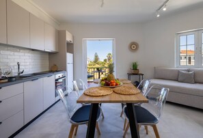 A modern kitchen with white cabinets, a wooden dining table with clear chairs, and a fruit bowl. - Terra Nuova Zante in Zakynthos (Zakynthos)