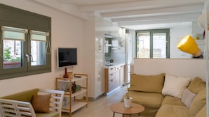 A modern living room with a sofa, TV, and a small table. - Eclectic Urban Nest in Heraklion (Heraklion)