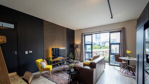 Una sala moderna con sofá, sillón amarillo y comedor con mesa y sillas.