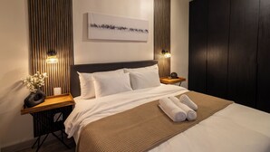 Una habitación de hotel moderna con una cama grande, paneles de madera en las paredes, un cuadro sobre la cama y dos lámparas de noche.