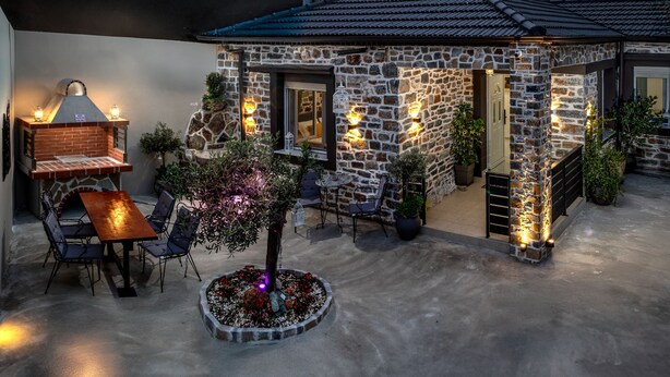 A stone building with a tiled roof, a brick oven, and outdoor seating. - The Coastal Rock House (Volos)