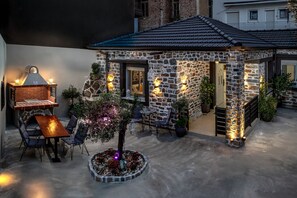 A stone building with a tiled roof, a brick oven, and outdoor seating.