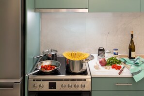 A kitchen with a stove, pots, a cutting board with vegetables, and a bottle of wine. - The Coastal Rock House (Volos)