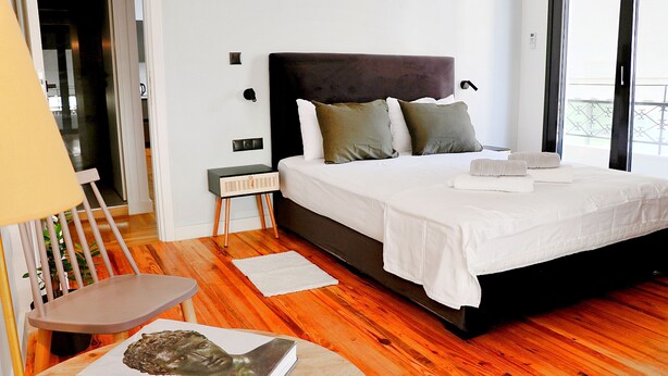 Une chambre à coucher moderne avec un grand lit, une table de chevet et une chaise.