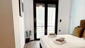 Une chambre d’hôtel avec un lit, une plante en pot et une vue sur un balcon.