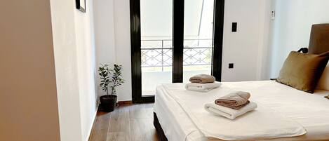 A hotel room with a bed, a potted plant, and a view of a balcony.