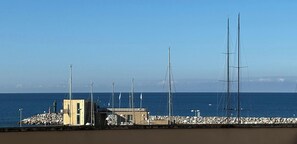 A coastal view with a rocky breakwater, a small building, and tall masts. - Apartment with parking space in central area-Rif. Silvestro (San Vincenzo)