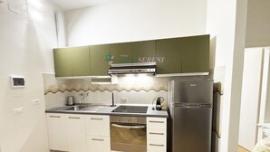 A compact kitchen with a stainless steel refrigerator, a built-in oven, and a sink. - 3 rooms 4 beds Conchiglia area. Il Gabbiano-Rif. Il gabbiano (San Vincenzo)
