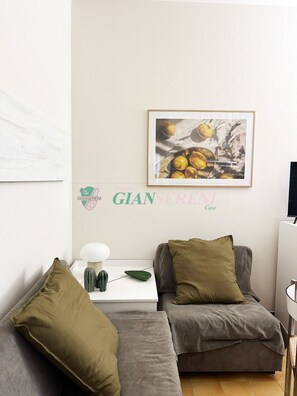 A living room with a grey sofa, a small table with a lamp, a cactus, and a framed picture on the wall. - 3 rooms 4 beds Conchiglia area. Il Gabbiano-Rif. Il gabbiano (San Vincenzo)