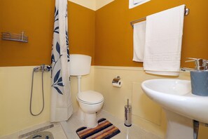 Une salle de bain comprenant des toilettes, un lavabo, une douche et un porte-serviettes.