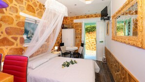 Ein Schlafzimmer mit Steinwand, einem Himmelbett, einem kleinen Tisch und einem Sessel.