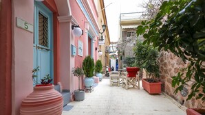 Eine schmale Straße mit Häusern an beiden Seiten, Blumentöpfen und Außenbestuhlung.