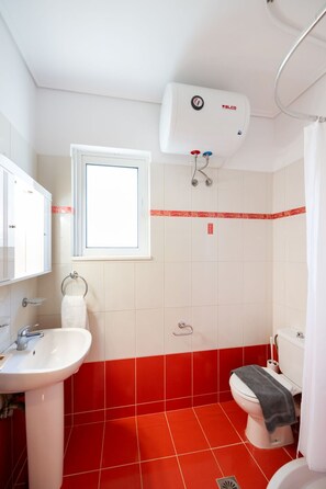 A bathroom with a white sink, a toilet, a window, and a shower. - Casa Vardani 3 Modern Central Apartment (Lefkada)