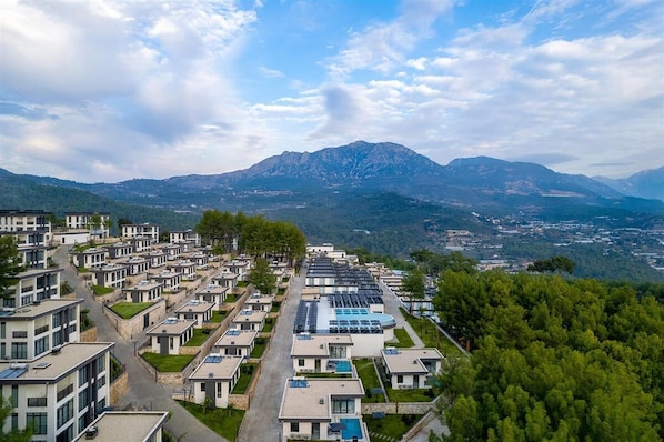 Zona residencial con modernos edificios de apartamentos, una piscina y montañas al fondo.
