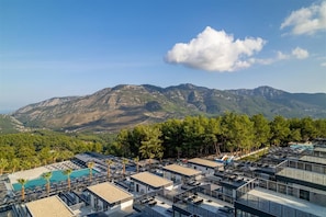 Un resort con varias construcciones, piscina y montañas al fondo.