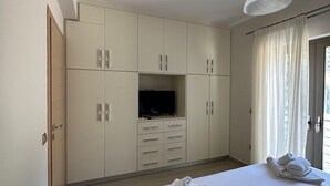 Et hotelværelse med en seng, et fjernsyn og et skab.