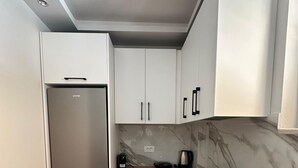 Una cocina moderna con armarios blancos, un refrigerador de acero inoxidable, una encimera negra y un salpicadero de mármol.