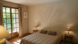 A bedroom with a large bed, two bedside tables with lamps, a window with curtains, and a wall with a leaf pattern. - 4-bedroom villa with private pétanque pool and padel court (Le Muy)