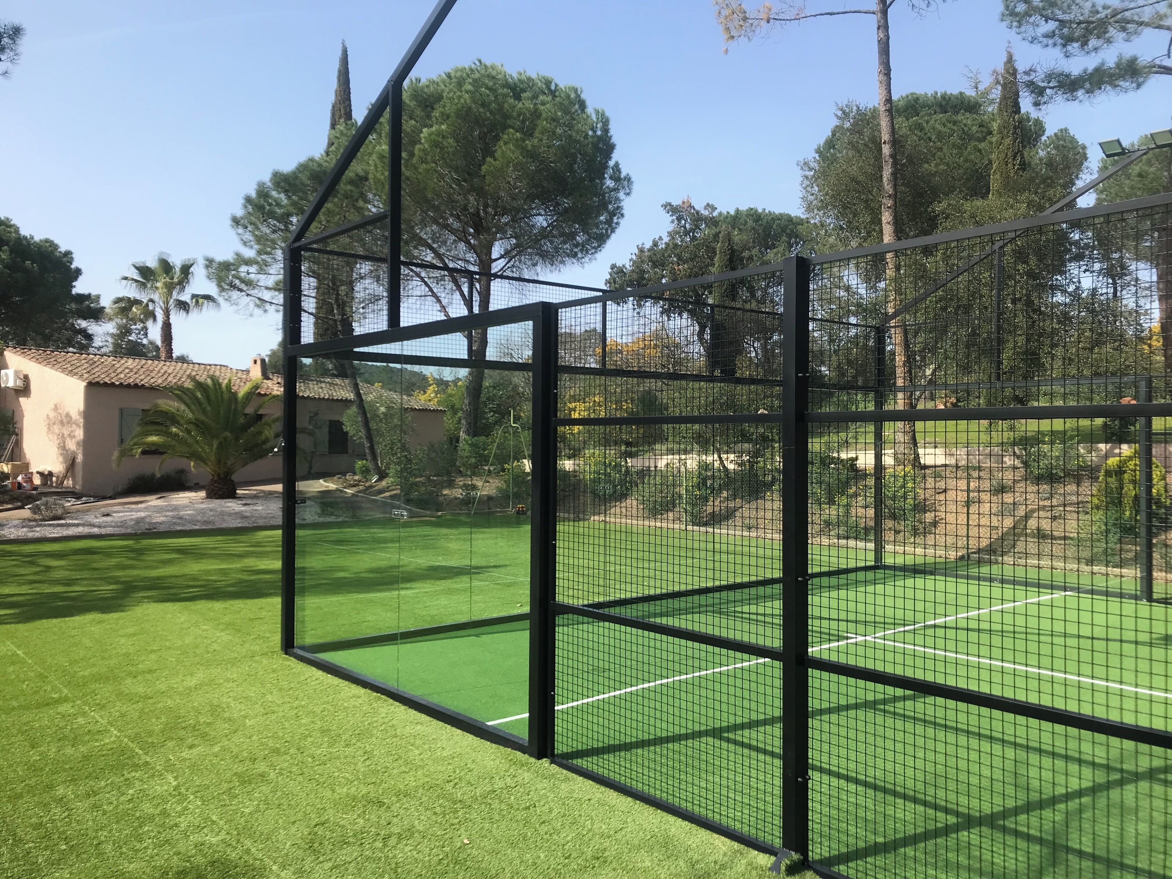 Un court de tennis avec un filet et des arbres tout autour.