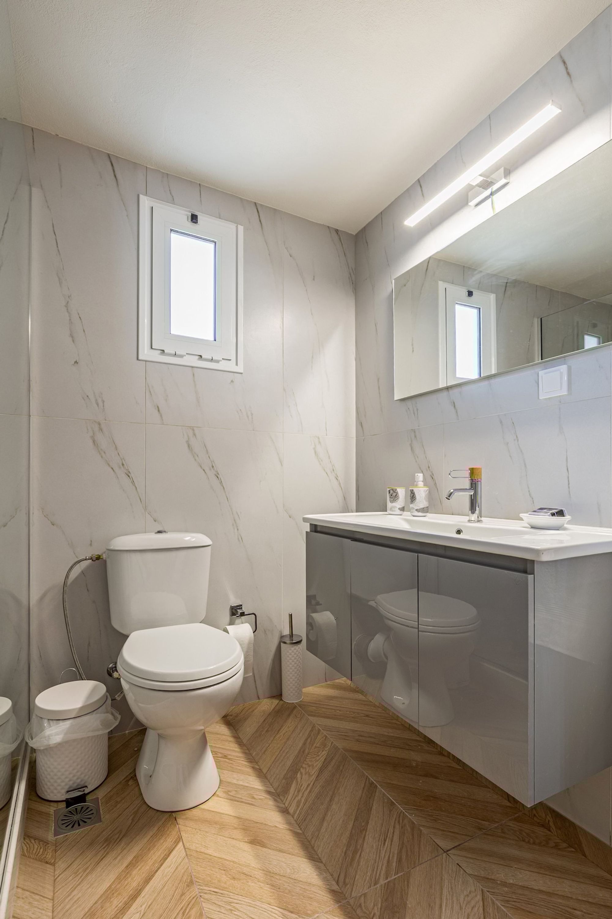 A modern bathroom with a toilet, sink, and mirror.
