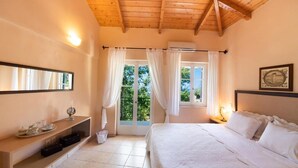 Una camera da letto con un letto, un comodino, uno specchio, una finestra con tende e vista su un balcone.