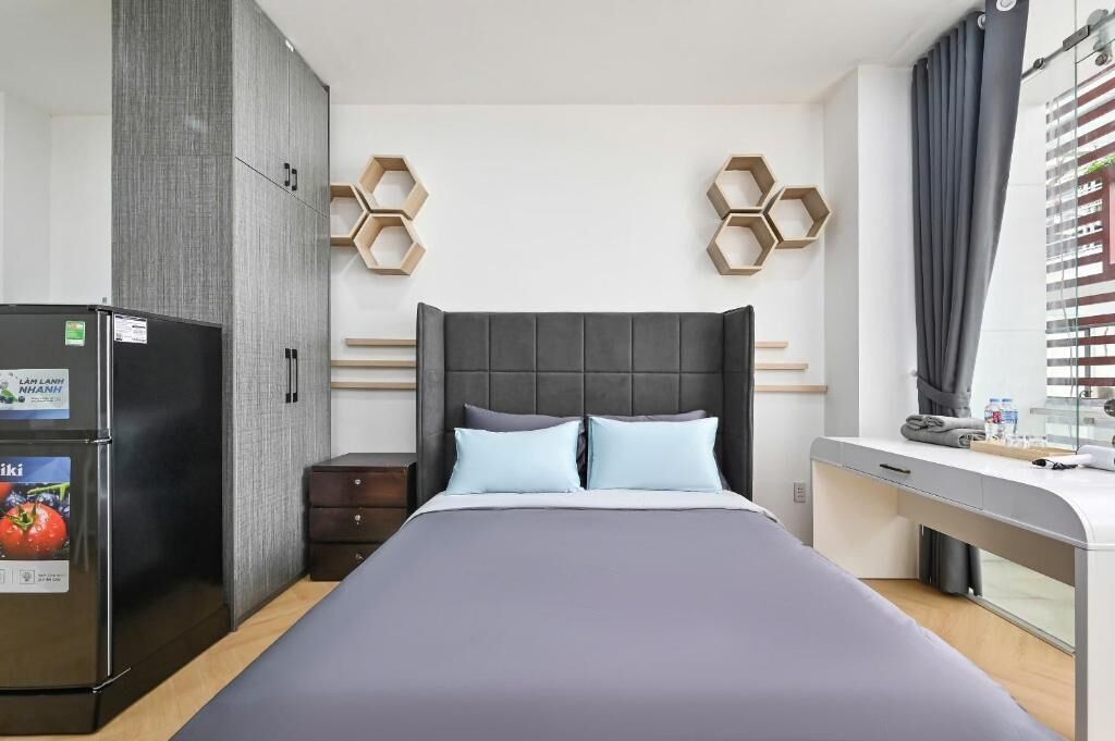 A modern hotel room with a bed, a desk, and a wardrobe.