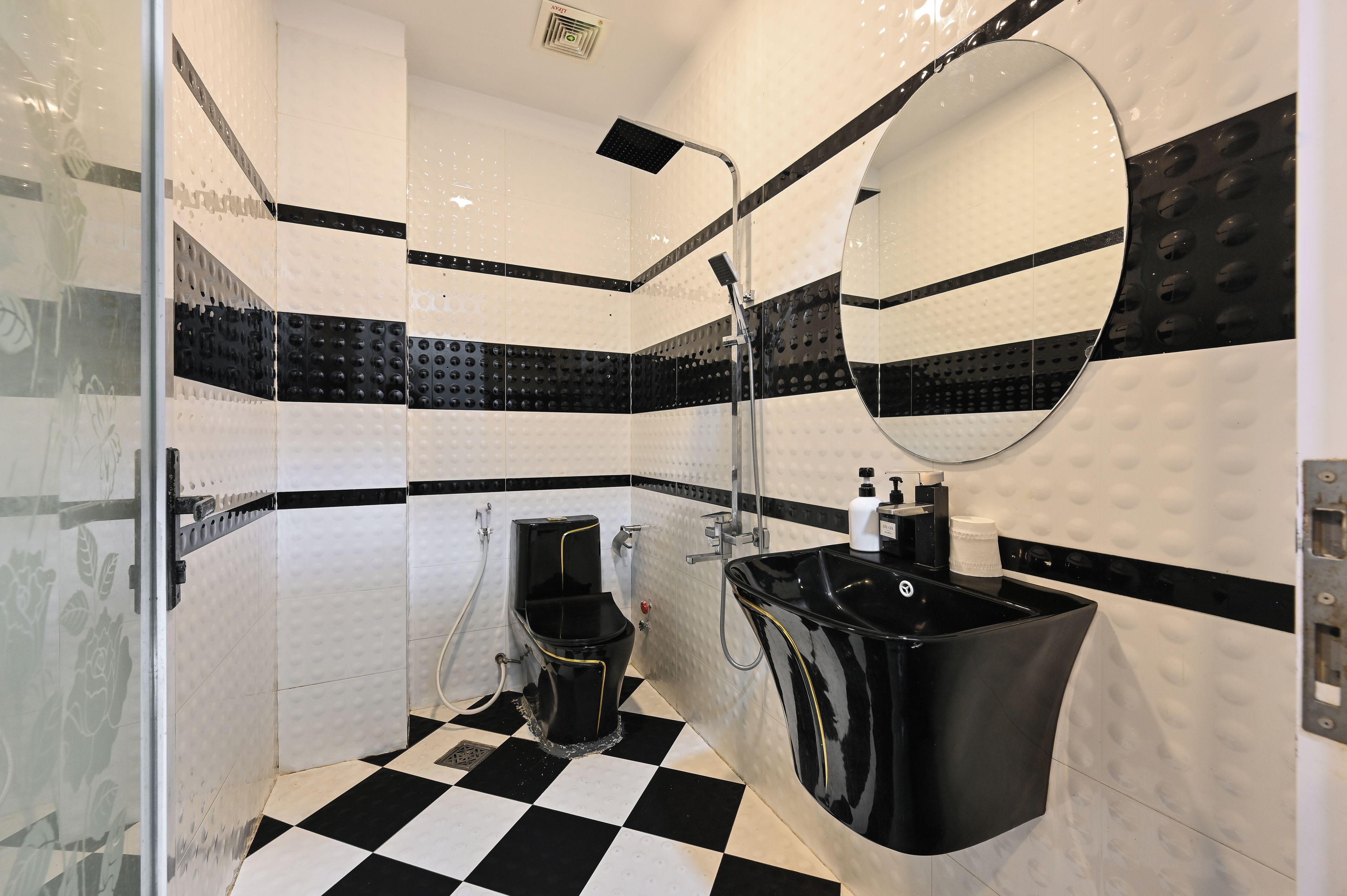 A bathroom with a black and white checkered floor, a black sink, and a mirror with a round frame.