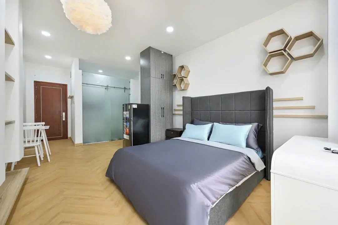 A modern bedroom with a large bed, a wardrobe, a desk, and a chair.