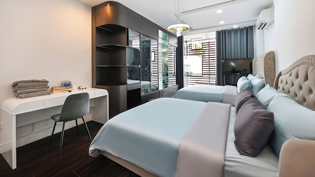 A modern hotel room with a desk, two beds, a chair, and a TV. - M Home Riverside (Ho Chi Minh City)