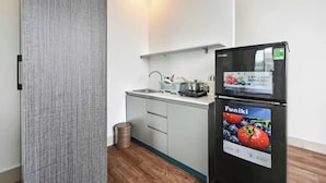 A compact kitchen with a refrigerator, a sink, and a small countertop. - M Home Riverside (Ho Chi Minh City)