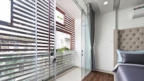 A bedroom with a bed, a glass door leading to a balcony, and a view of the outside. - M Home Riverside (Ho Chi Minh City)