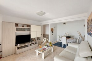 A living room with a TV, sofa, coffee table, and dining area. - Casa Pino with Sea View, Balcony, and Wi-Fi (Furore)