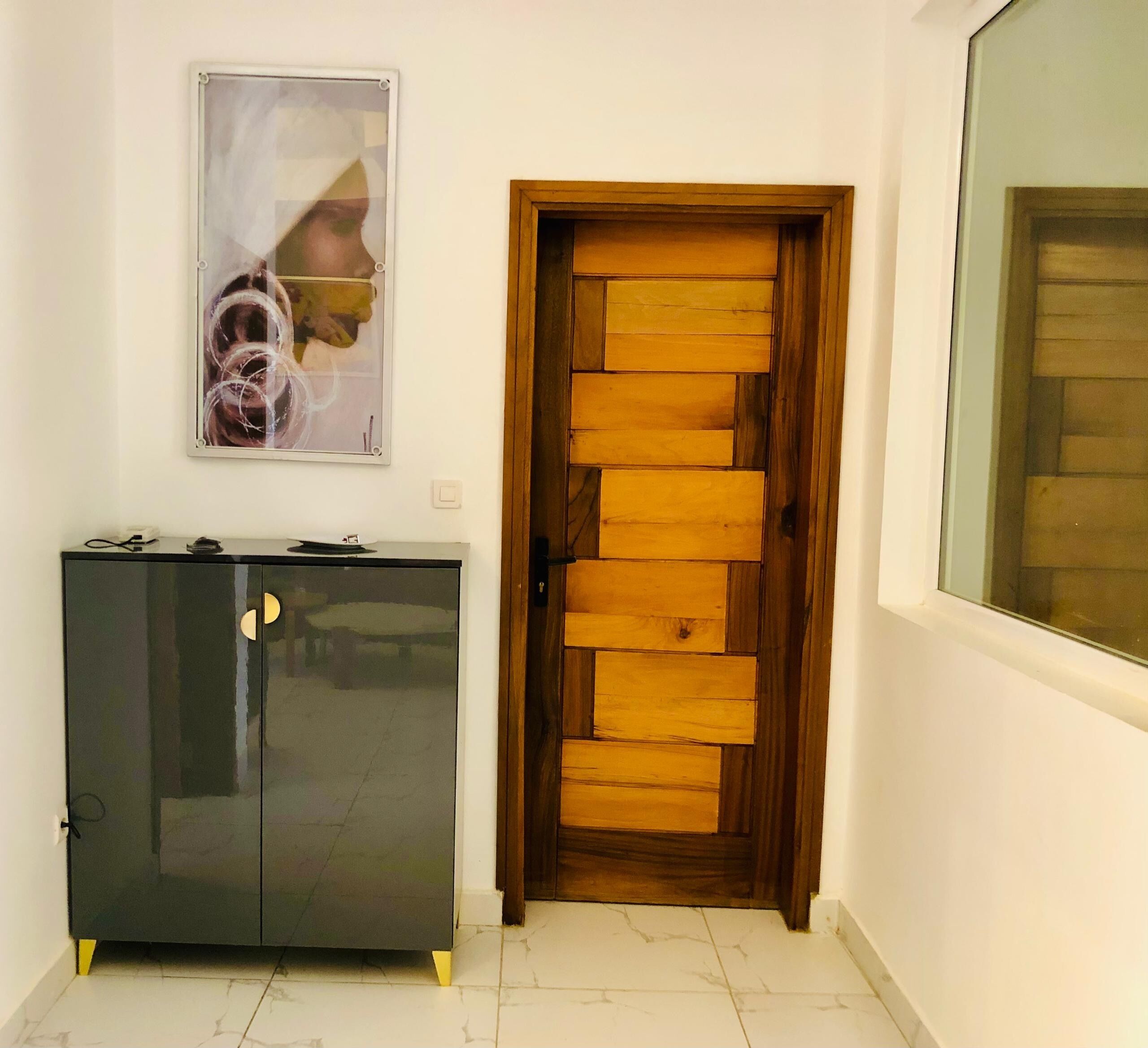 A hallway with a wooden door, a dark cabinet, and a framed picture on the wall.