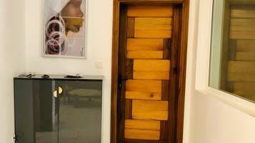 A hallway with a wooden door, a dark cabinet, and a framed picture on the wall.