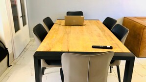 Una sala de conferencias con una mesa de madera, sillas negras, una computadora portátil y un control remoto sobre la mesa.