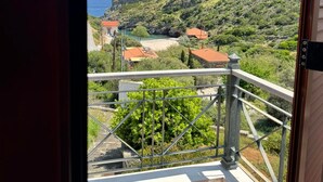 A balcony with a view of a hillside and the sea.