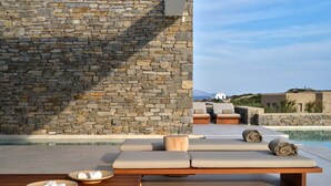 Un muro de piedra, mobiliario exterior y una piscina.