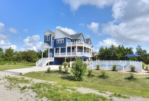 A two-story house with a balcony, a porch, and a white fence.