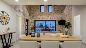 Un comedor con pared de piedra, un reloj grande y un televisor montado en la pared.