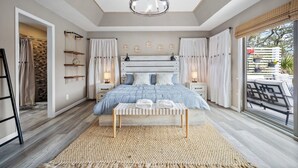 Un dormitorio con una cama grande, mesitas de noche, un candelabro y vistas al exterior.
