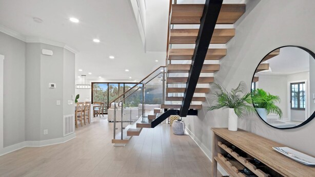Un intérieur moderne avec un escalier, une console en bois et un miroir.